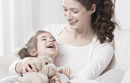 Mother holding child in her arm - the child is holding a stuffed animal.